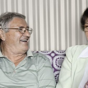 Old couple are sitting on a couch together and smiling